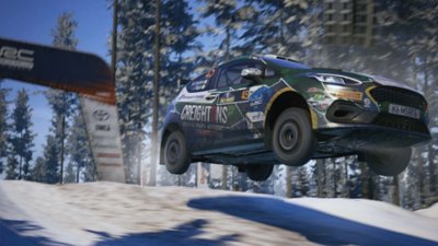 EA Sports WRC screenshot showing William Creighton's M-Sport Poland Fiesta Rally3 soaring through the air in a snowy forest