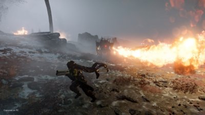 Helldivers 2 – Capture d'écran de la version PC montrant un robot armé d'un lance-flammes et un soldat en train de fuir.