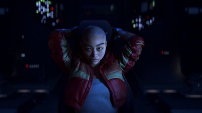 Intergalactic: The Heretic Prophet screenshot showing main character Jordan, wearing her signature red bomber jacket, reclining in a chair