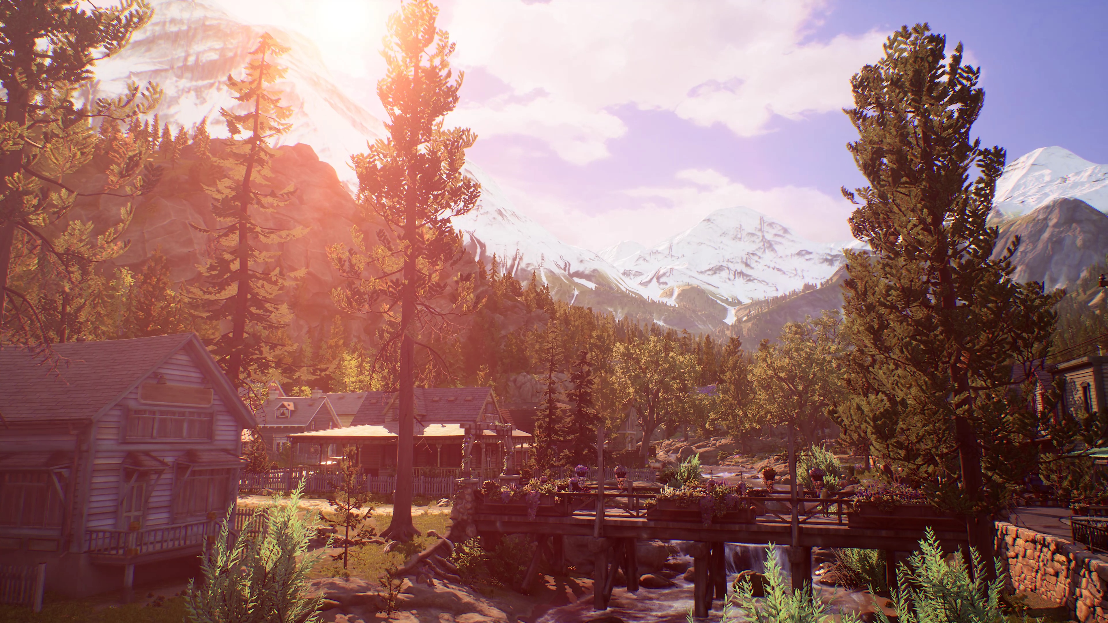 Life Is Strange True Colors screenshot showing a beautiful small town with a bridge across a small river. Mountains can be seen in the distance