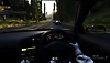 Vue à la première personne d'un pilote tenant le volant d'une voiture, roulant sur une section boisée d'un circuit dans Gran Turismo 7.
