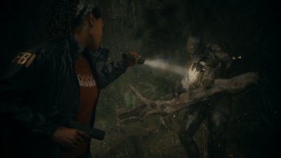 《Alan Wake 2》螢幕截圖，呈現薩佳·安德森把手電筒照在拿著巨大樹枝的怪物敵人身上