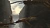 Baby Steps – snímek obrazovky, na kterém se hrdina pokouší opatrně přejít po vratkém dřevěném mostě na vrcholu hor 