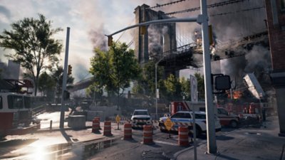 A street blocked off by emergency services while a New York City bridge burns in the background.