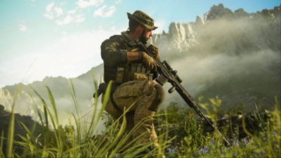 Captura de tela de Call of Duty: Modern Warfare III apresentando um integrante da Força-Tarefa 141 agachado na relva contra uma paisagem montanhosa