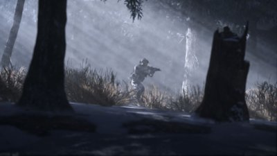 Call of Duty: Modern Warfare III – snímek obrazovky zobrazující operativce, který se zdviženou zbraní prochází zalesněnou oblastí
