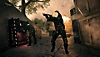 Bir karakter silahını doğrulturken bir diğeri silah zulasını yağmalarken gösteren Call of Duty: Warzone ekran görüntüsü