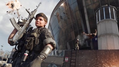 Call of Duty: Warzone screenshot showing an Operator posing with her weapon in the foreground while a helicopter explodes in the sky and another Operator blasts a rival off the side of Verdansk Stadium.