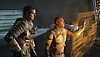 Snímek obrazovky ze hry Dead Space, na kterém Isaac a další postava interagují s holografickým displejem.