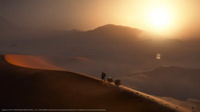 Death Stranding 2: On the Beach screenshot showing Sam walking across a sand dune with cargo