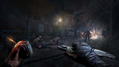 Dying Light: The Beast – Screenshot aus der Perspektive des Spielercharakters, der mit einem Sprengsatz in der einen und einem Messer in der anderen Hand auf einen Infizierten zugeht