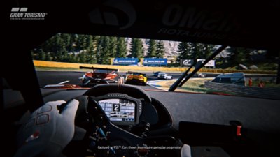 A screenshot of Gran Turismo 7 from inside the car driving along a corner with competing cars ahead of the player