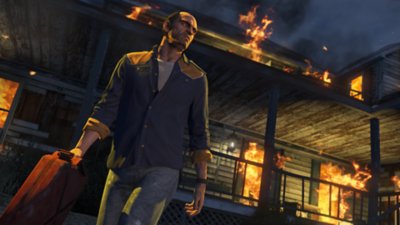 《Grand Theft Auto V》的屏幕截图，所示为主角崔佛拿着一个汽油桶从燃烧的建筑物中走出来