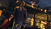 Captura de pantalla de Grand Theft Auto V que muestra al personaje principal, Trevor, alejándose de un edificio en llamas mientras sostiene un bidón de gasolina
