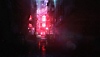 Snímek obrazovky ze hry Hitman World of Assassination zobrazující uličku osvětlenou červeným neonovým světlem