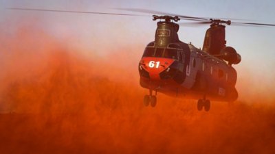 Microsoft Flight Simulator 2024 screenshot showing a tandem rotor aircraft taking off billowing up red sand