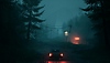 Pacific Drive – zrzut ekranu przedstawiający samochód na leśnej drodze, ze zrujnowaną stacją benzynową w pewnej odległości
