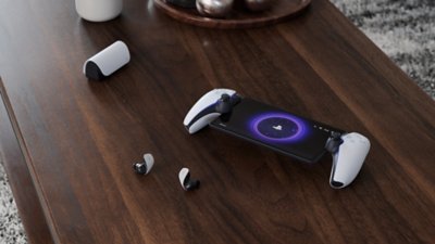 PlayStation Portal remote player with PULSE explore earbuds on a table