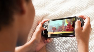 a person playing a PS Vita console showing hands playing LittleBigPlanet