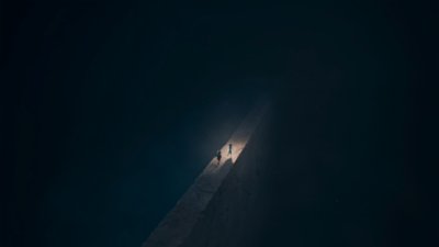 Captura de pantalla de Reanimal que muestra a los hermanos cruzando un puente de piedra a oscuras