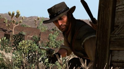 Red Dead Redemption screenshot showing John Marston taking cover with his pistol drawn