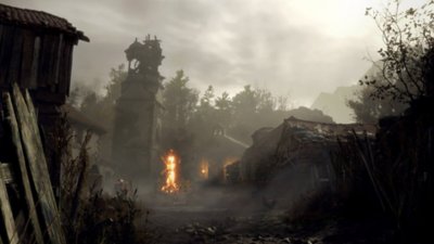 Resident Evil 4 screenshot featuring a dilapidated village with a bonfire at its centre