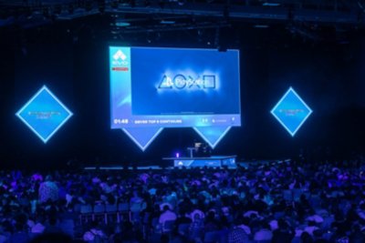 EVO 2024の写真 大勢の観客がいる中、イベントメインステージの頭上にある大型スクリーンにPlayStationのシンボルが写っている。