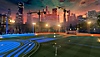 ภาพหน้าจอ Rocket League แสดงให้เห็นสนามแข่งที่มีเส้นขอบฟ้าของเมืองเป็นฉากหลัง