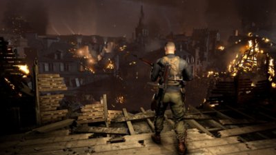 Sniper Elite 5 스크린샷, 불타는 건물이 있는 마을을 바라보는 캐릭터