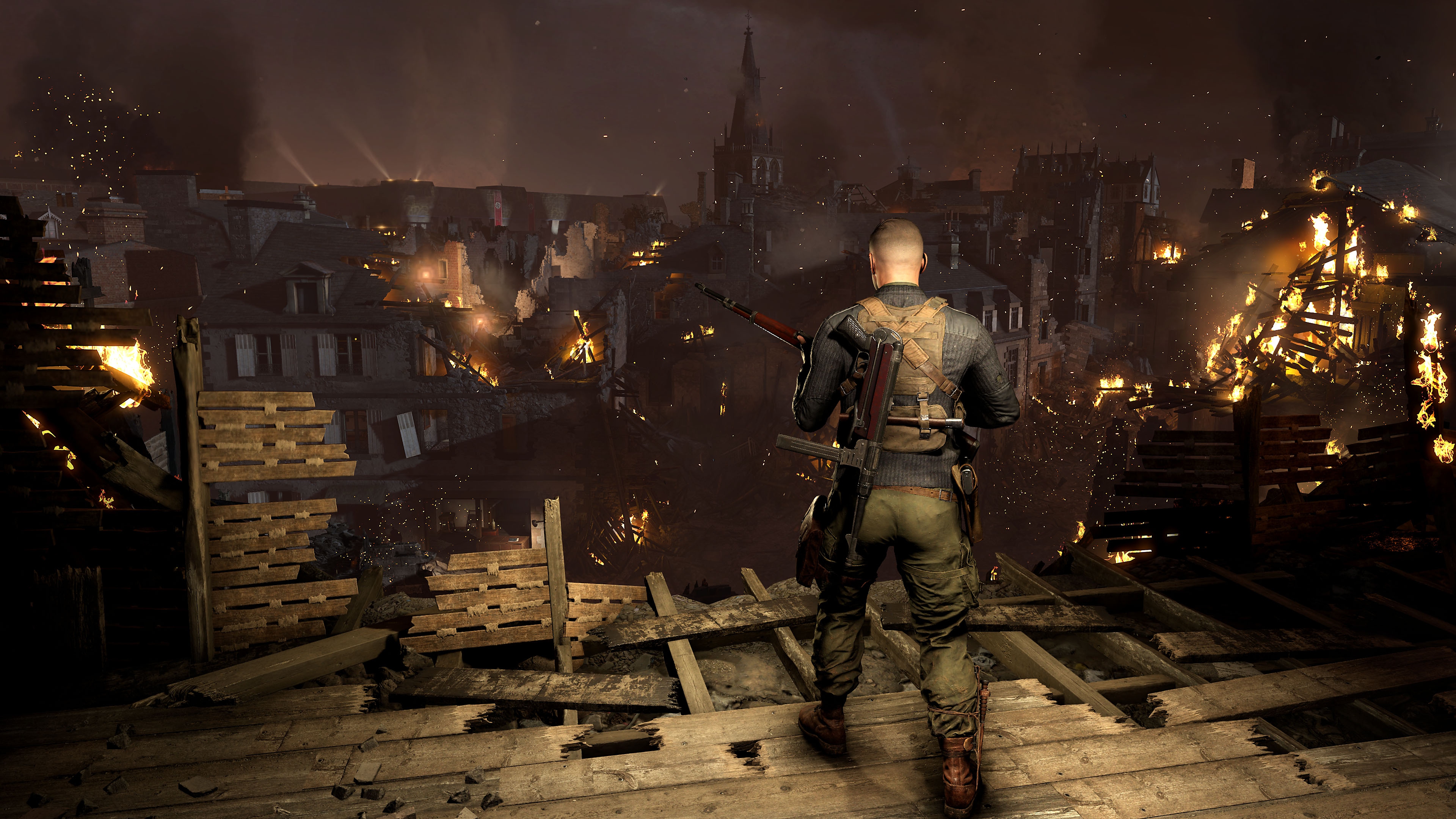 Sniper Elite 5 screenshot showing a character looking out over a town with buildings on fire