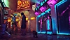 Stray – snímka obrazovky zobrazujúca mačku kráčajúcu neónovo osvetlenou ulicou