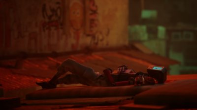 『Stray』スクリーンショット 床に横たわるロボットの隣で丸くなって眠る主人公の猫