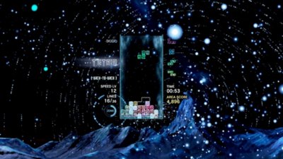 Tetris Effect Connected 스크린샷, 빙빙 도는 별로 가득한 하늘을 배경으로 게임 플레이 중