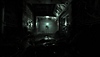 Screenshot von The Callisto Protocol, der die Silhouette einer Kreatur zeigt, die am Ende eines Korridors steht