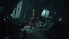 The Callisto Protocol screenshot showing the main character in a prison jumpsuit looking through a window
