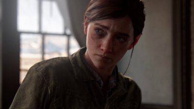 The Last of Us Part 2 pro PC – snímek obrazovky zobrazující Ellie v místnosti, jak se dívá na neviděnou postavu