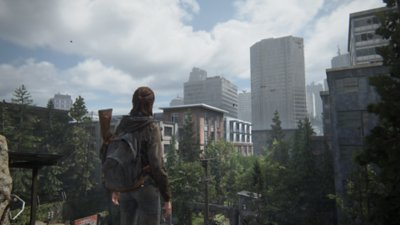 The Last of Us Part II Remastered screenshot showing Ellie looking out across the overgrown ruins of downtown Seattle