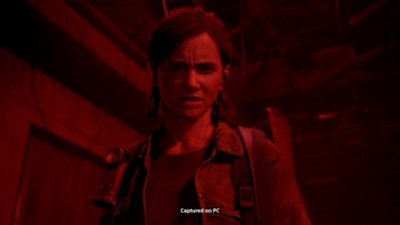 The Last of Us Part II Remastered for PC screenshot showing Ellie bathed in red light.