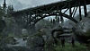 Screenshot van The Last of Us: Remastered met daarop Joel en Ellie die voor een verlaten brug staan