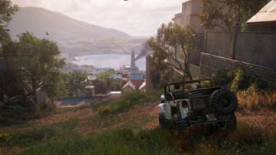 لقطة شاشة من Uncharted 4 تعرض "ناثان" و"سولي" يقودان سيارة jeep على جانب التل باتجاه مستوطنة 